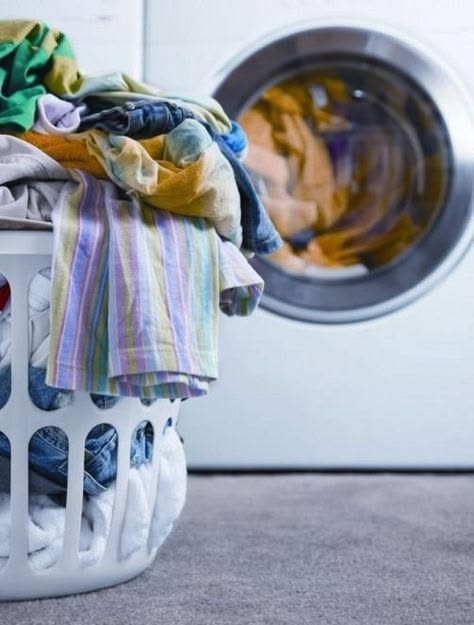 A basket of freshly laundered clothes beside the washer